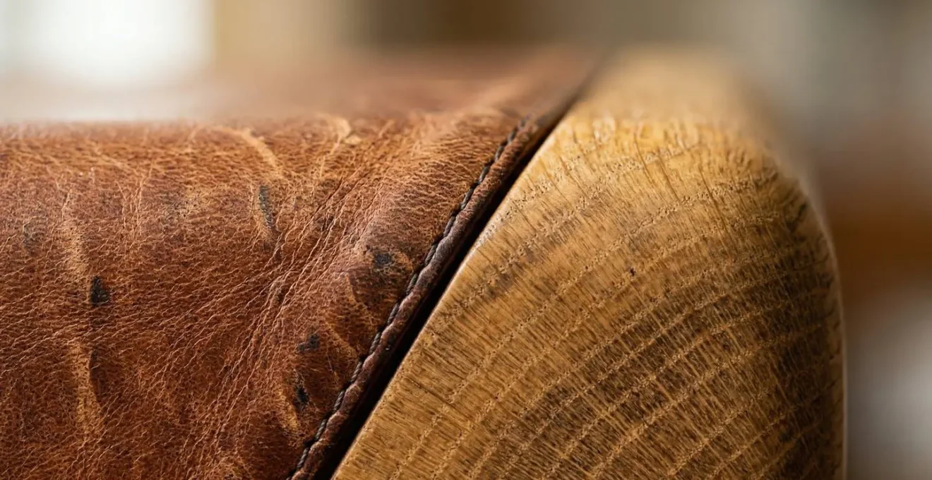 Vue macro détaillée montrant la patine naturelle du cuir vieilli contre du bois de chêne patiné